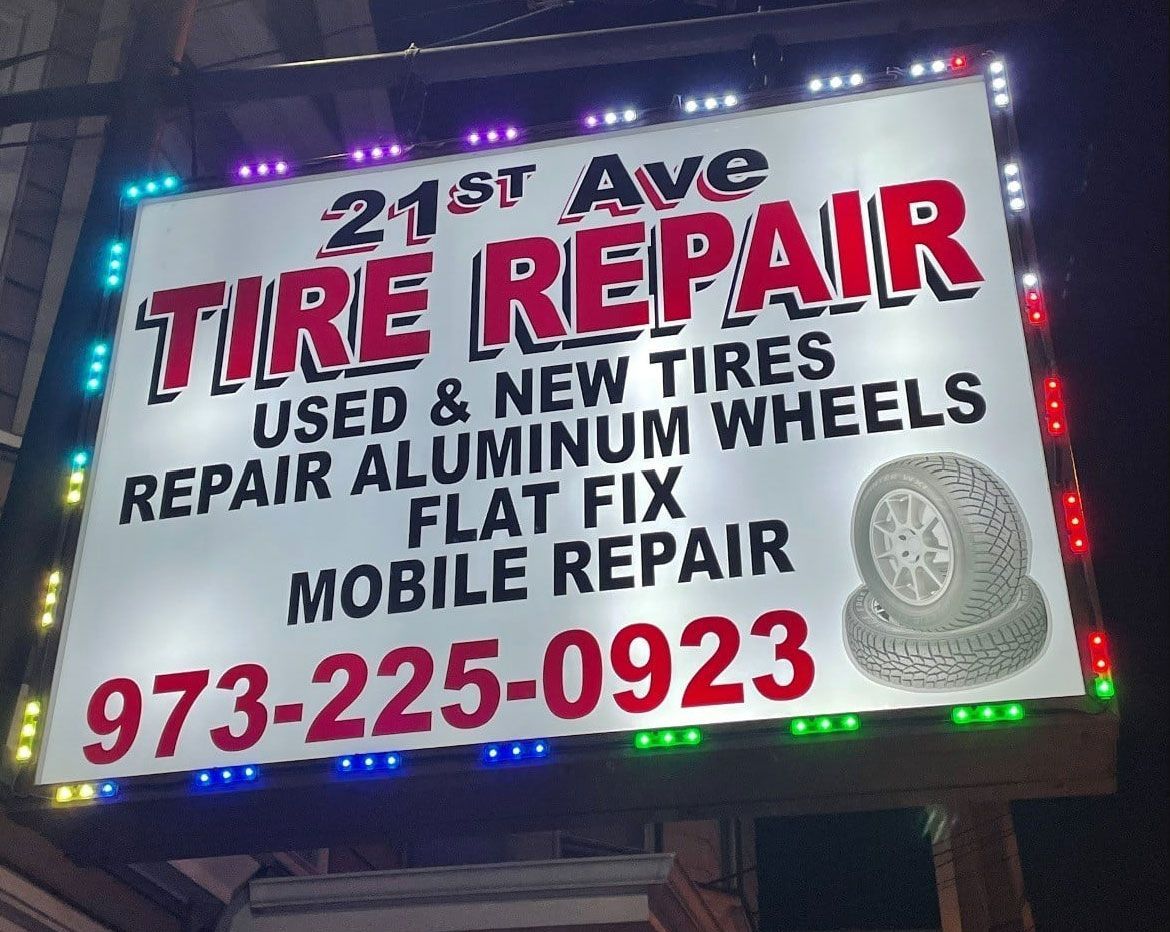 A sign for 21st ave tire repair is lit up at night
