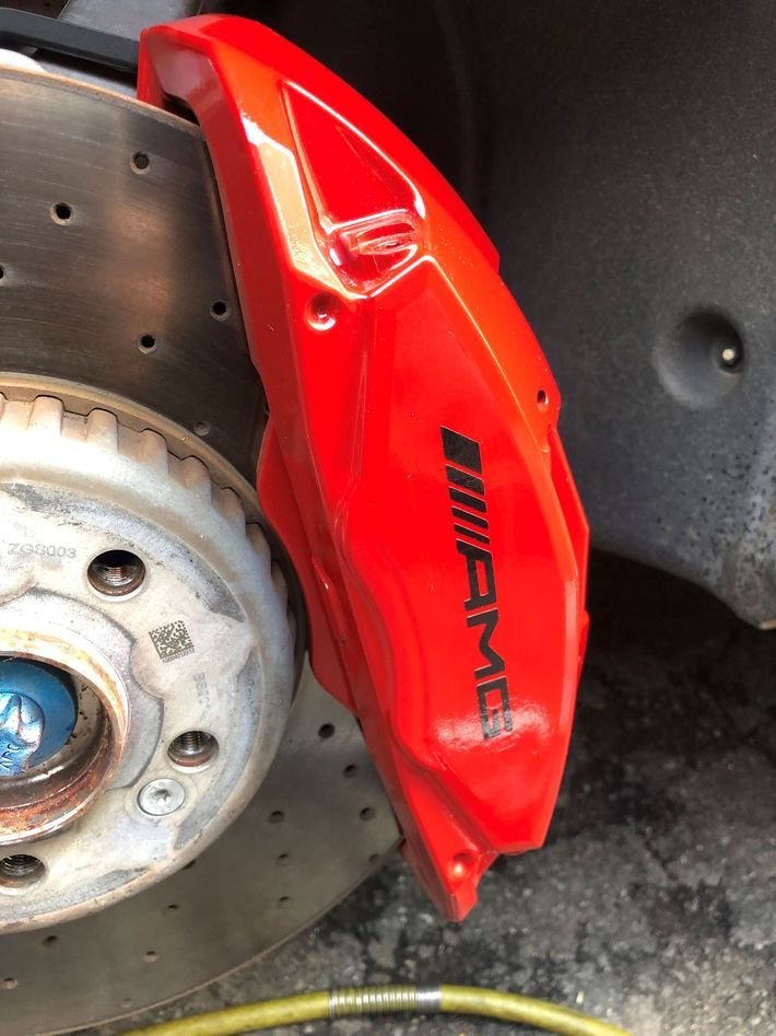 A close up of a red amg brake caliper on a car