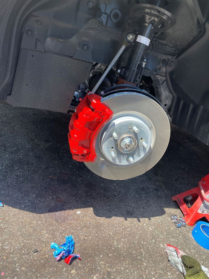 A car with a red brake caliper is sitting on the ground.
