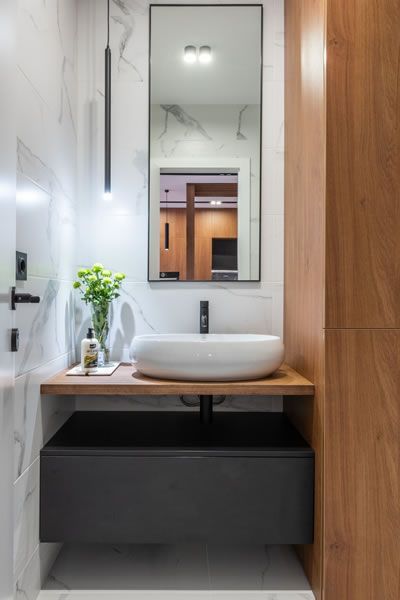 a small bathroom remodel with a sink, mirror, and wooden cabinets.