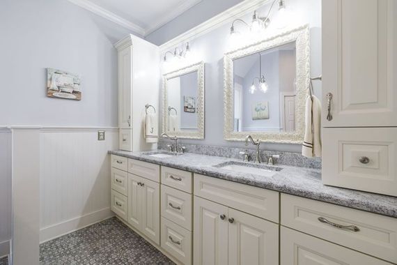 a bathroom remodel with two sinks, two mirrors, and white cabinets.