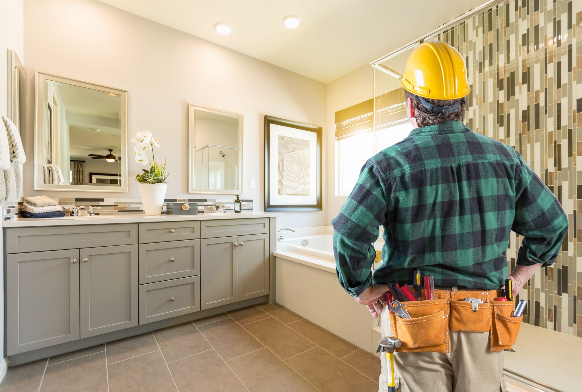 a contractor wearing a hard hat is standing in a bathroom, ready to provide a Bathroom Remodeling Quote for those who call.