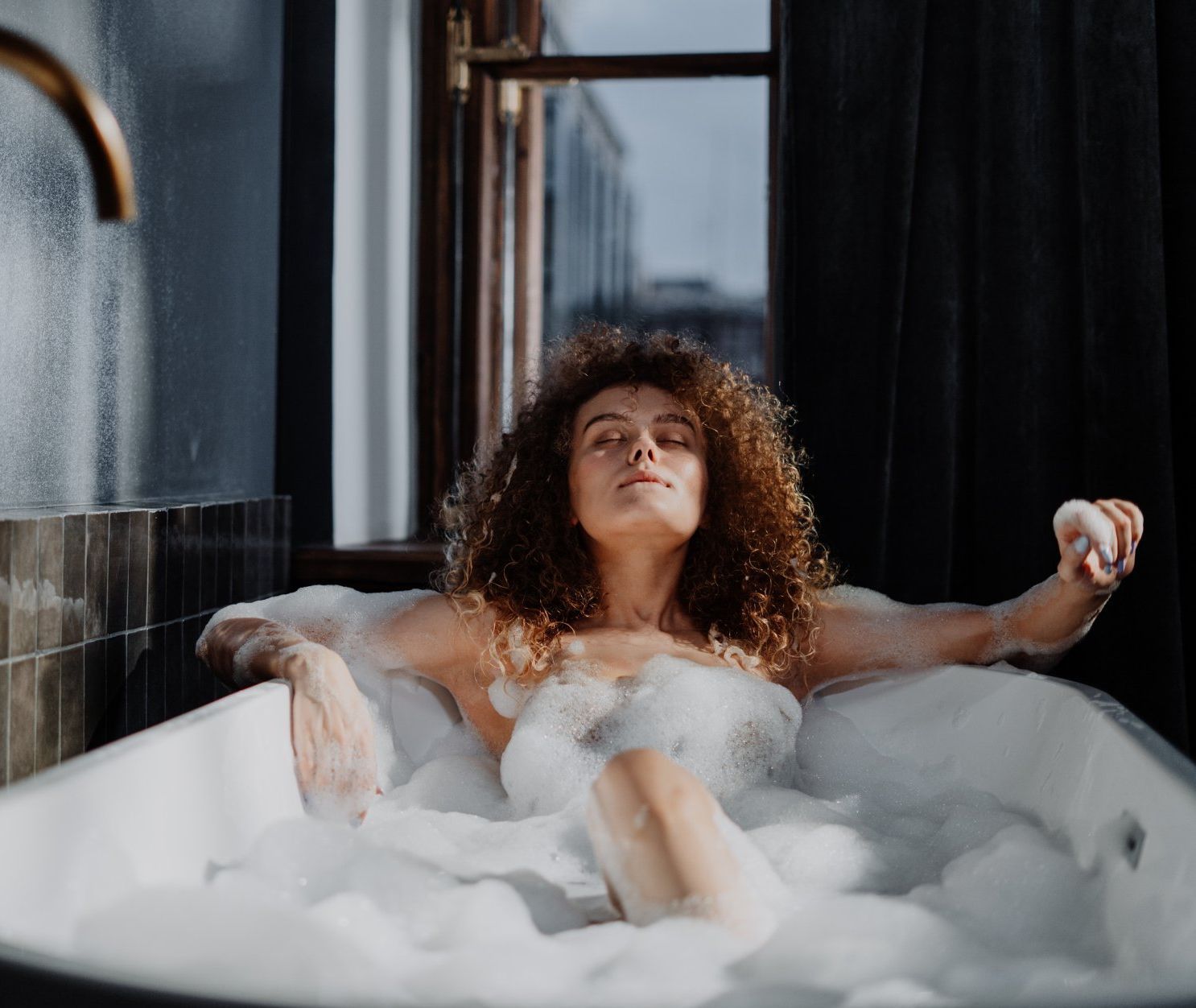 a woman is taking a bath in a bathtub filled with foam. Bathroom Gut and Remodel Cost in 2024