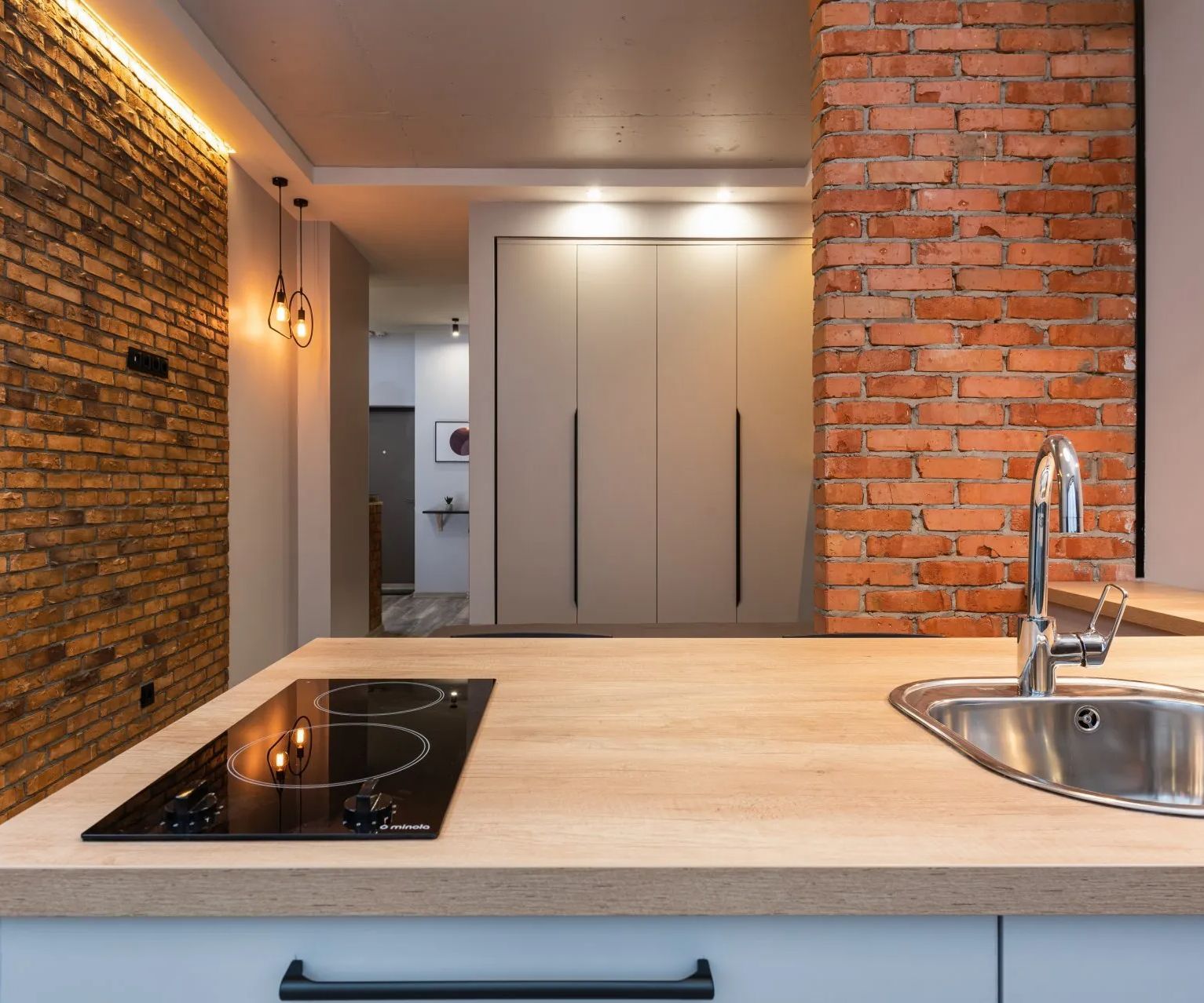 a kitchen with a stove top oven , sink , and brick wall. 5 Kitchen Trends for 2024
