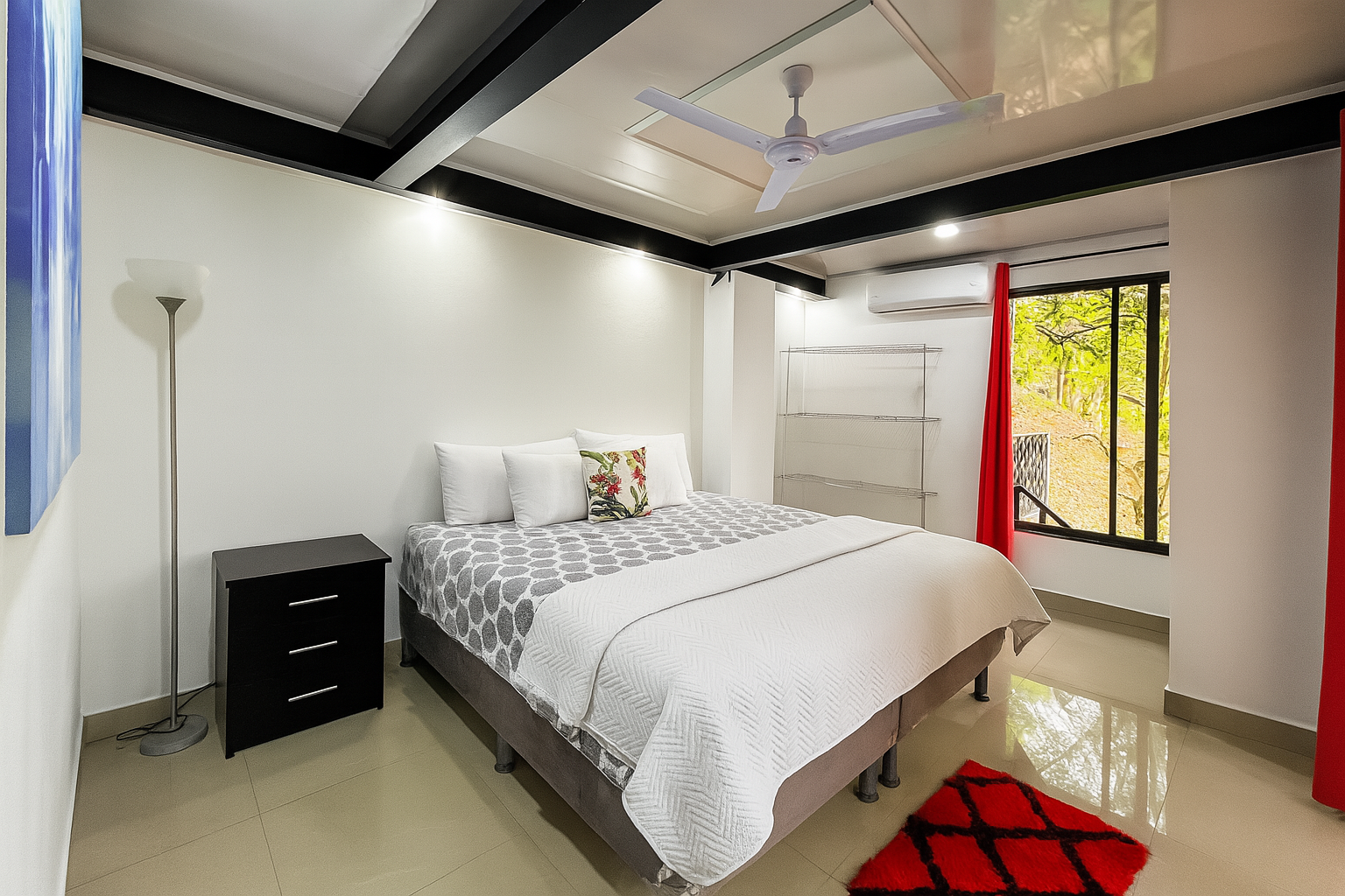 Un dormitorio con una cama roja y cortinas azules.