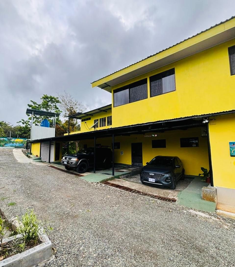 Un edificio amarillo con coches aparcados delante.