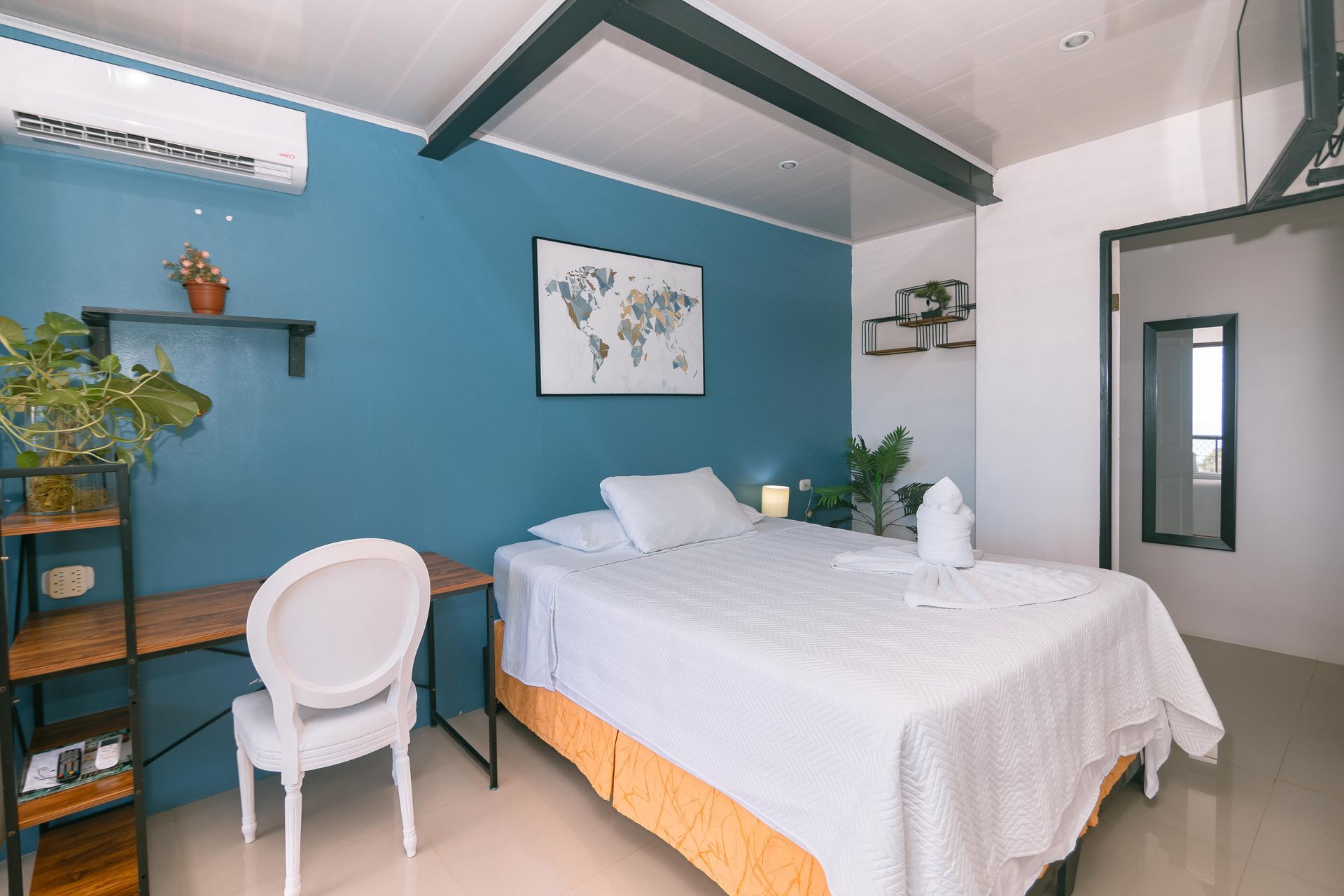 Un dormitorio con una cama, una silla, un escritorio y un mapa en la pared.