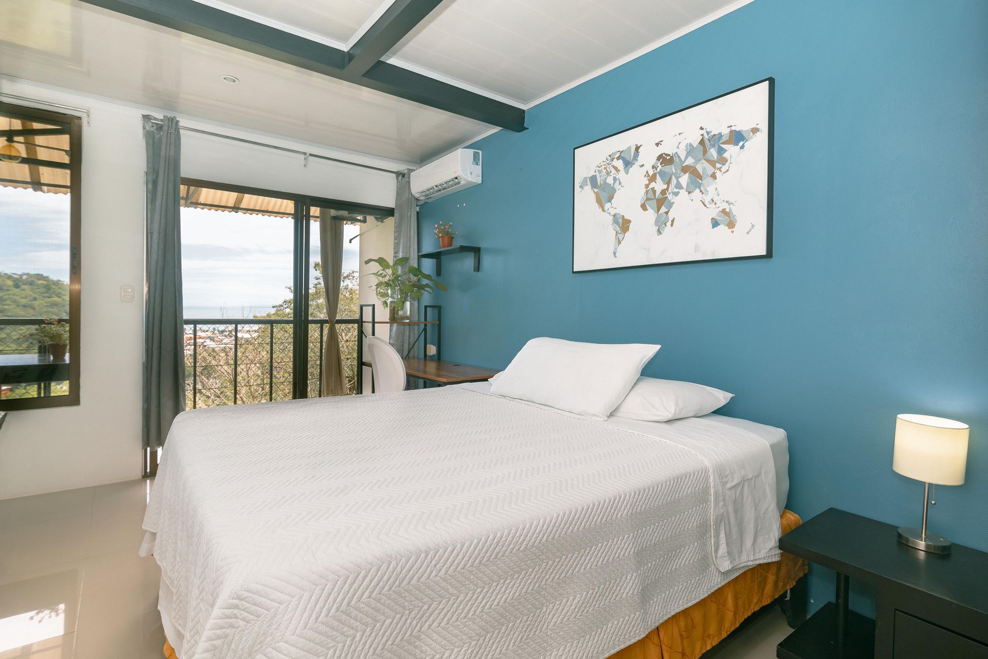 Un dormitorio con una cama, una silla, un escritorio y un mapa en la pared.