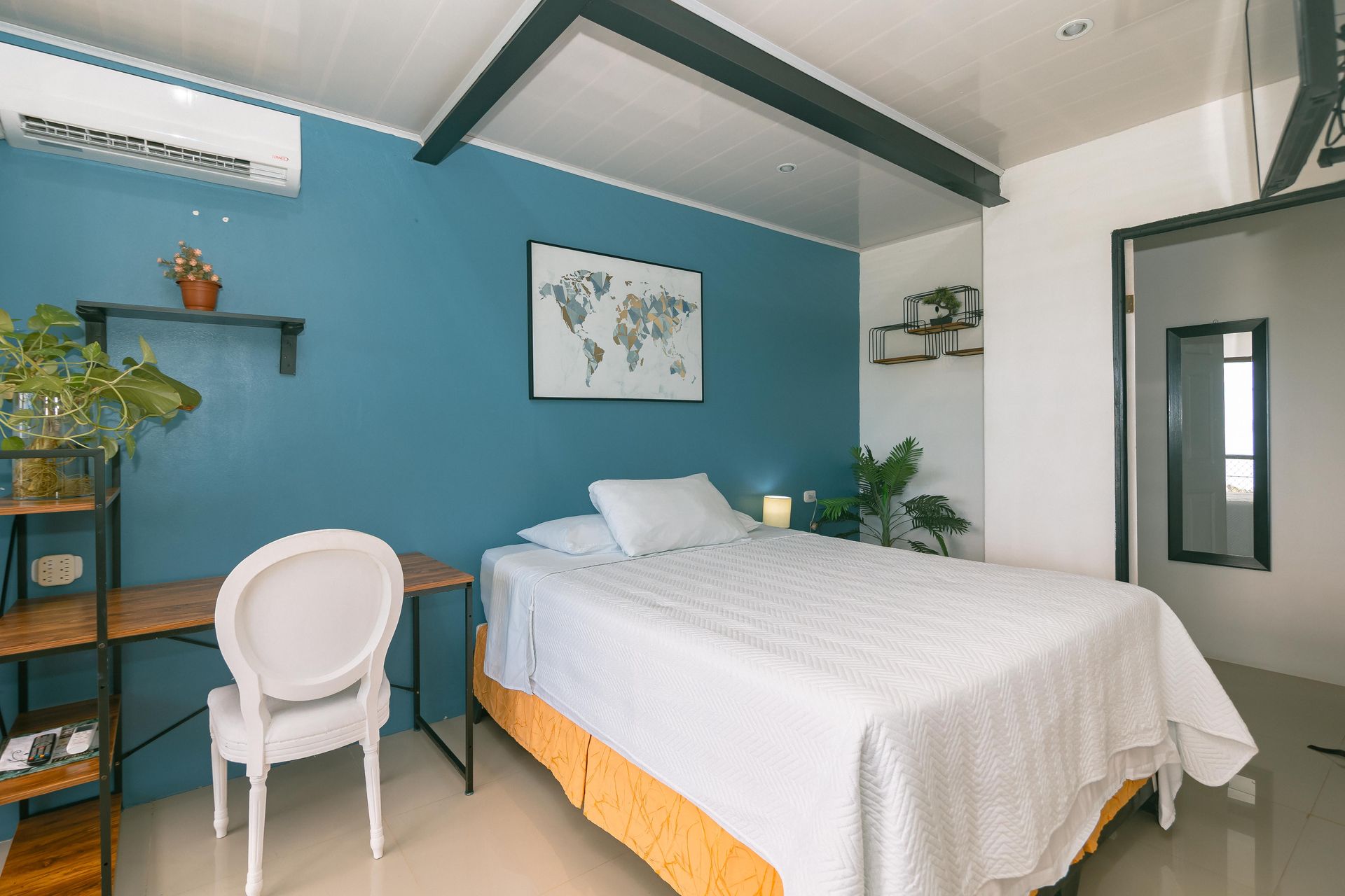 Un dormitorio con una cama, una silla, un escritorio y un mapa en la pared.
