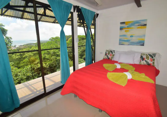 Un dormitorio con una cama roja y cortinas azules.