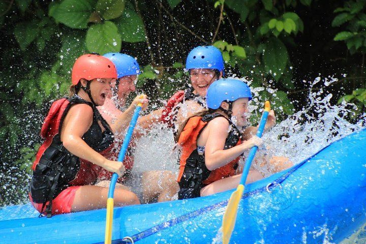 Un grupo de personas está haciendo rafting por un río en una balsa naranja.