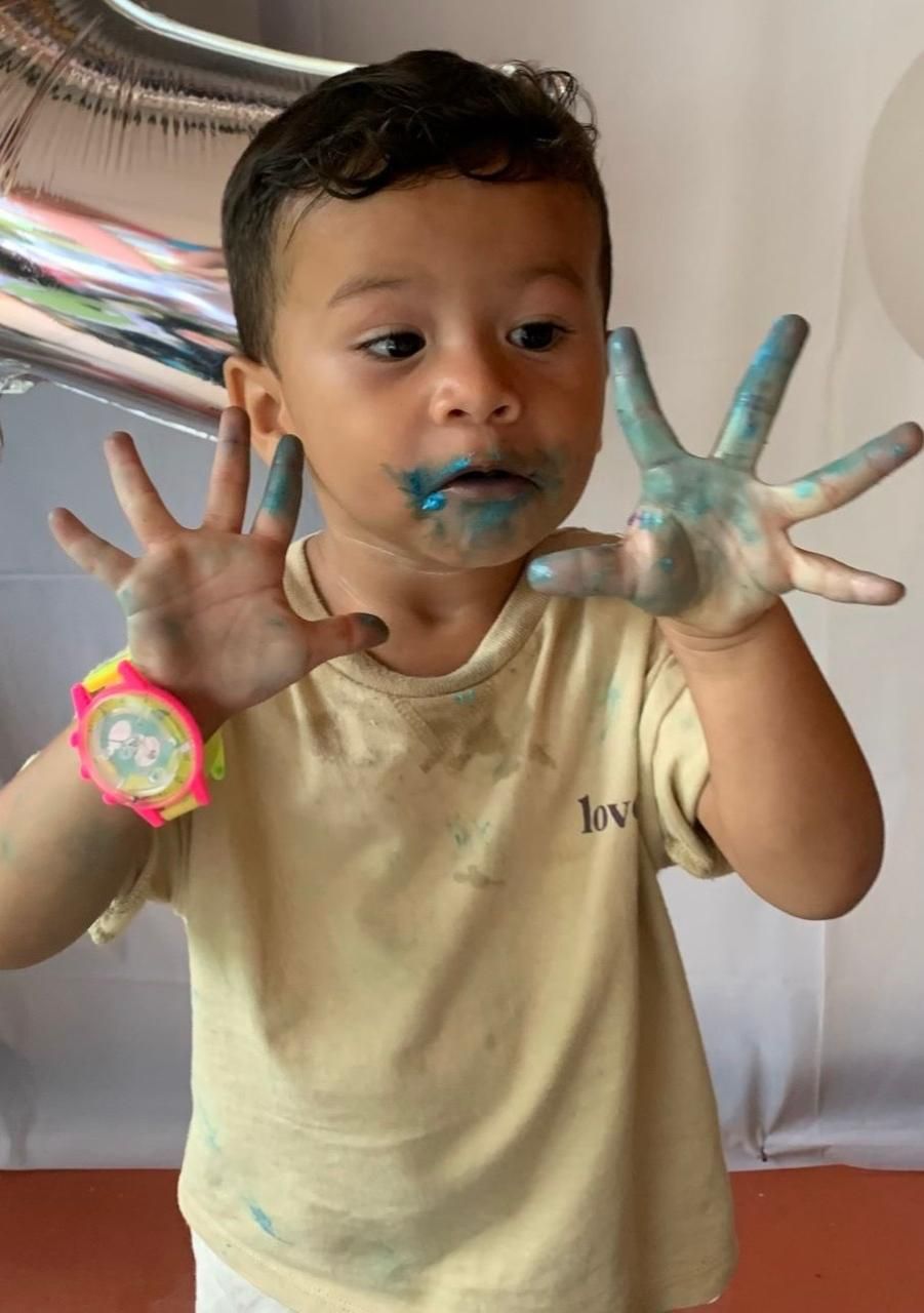 Un niño pequeño con las manos cubiertas de pintura azul