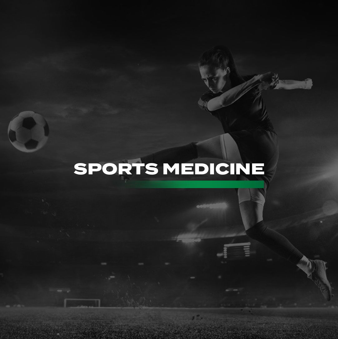 A soccer player is kicking a soccer ball on a field with the words sports medicine in front of her.