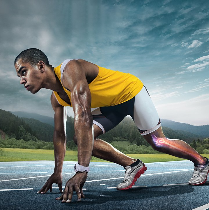 A man in a yellow tank top is getting ready to run on a track