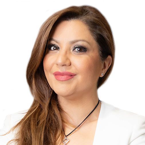 A woman wearing a white jacket and a necklace is smiling.