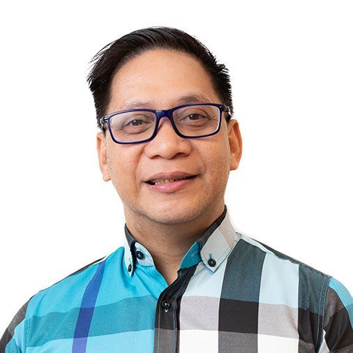 A man wearing glasses and a plaid shirt is smiling for the camera.