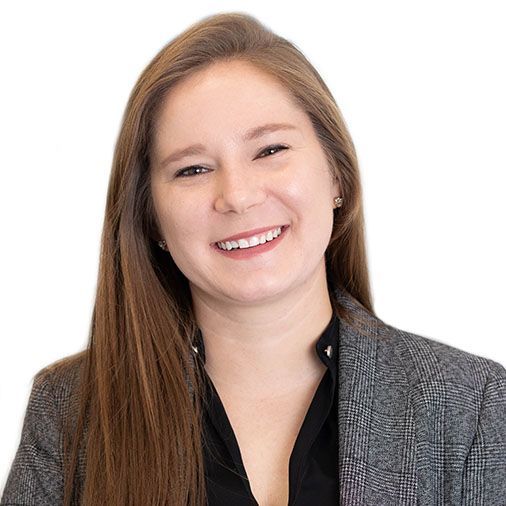 A woman wearing a gray jacket and a black shirt is smiling.