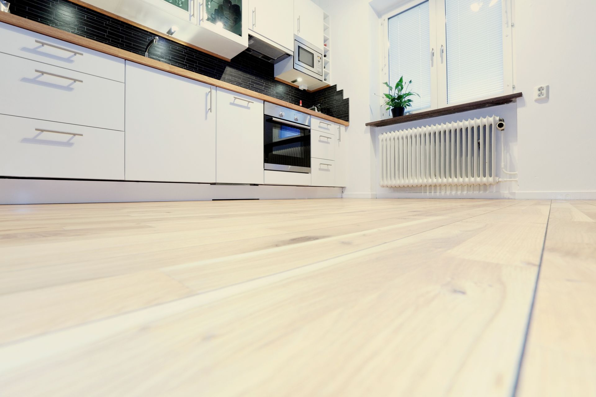 A kitchen with white cabinets and a wooden floor
