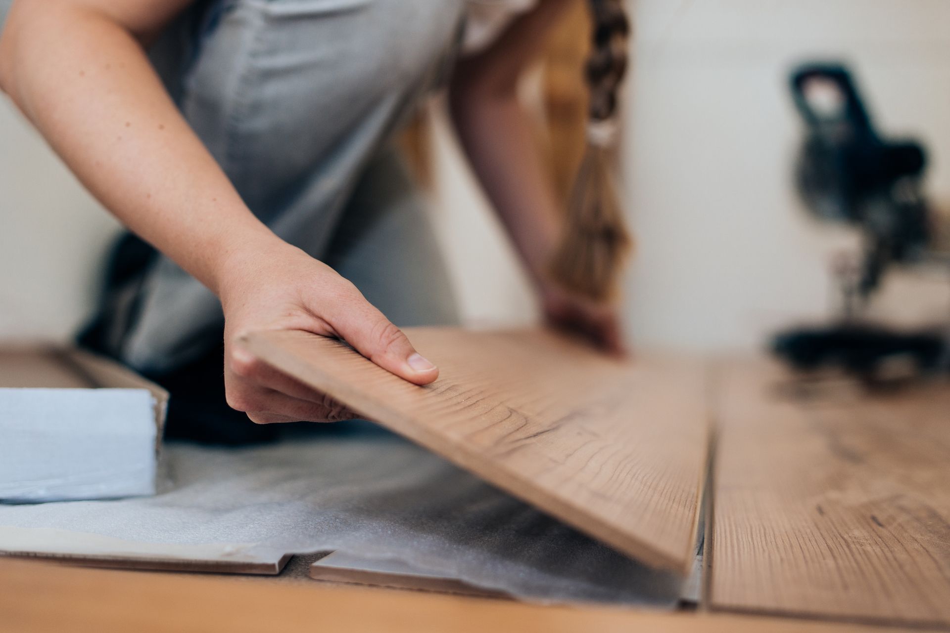 A person is installing a wooden floor in a room.