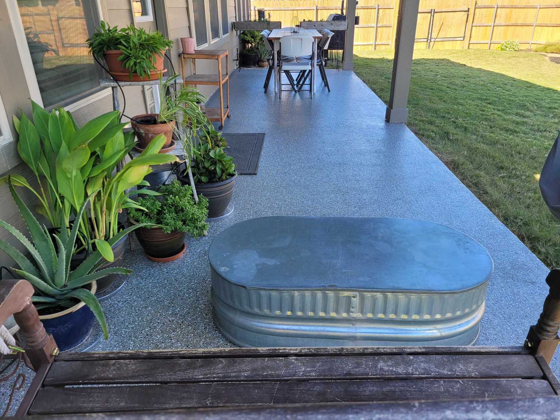 a metal trough is sitting on a porch next to a table and chairs .