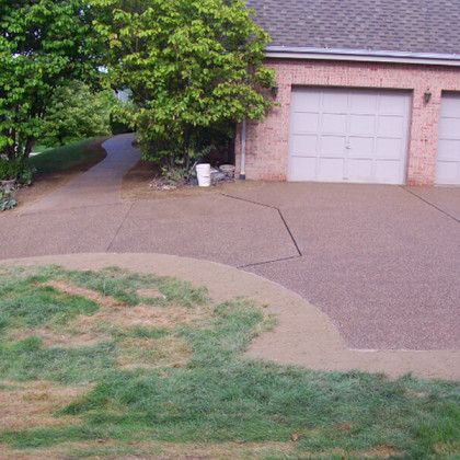 A driveway leading to a brick house with two garages.