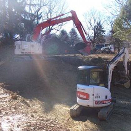 A bobcat excavator is digging a hole in the dirt.