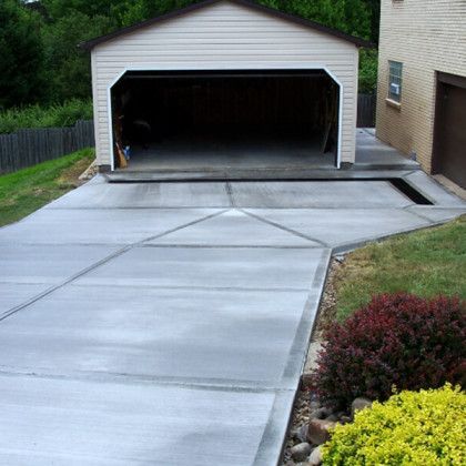 A concrete driveway leading to a garage with the door open.