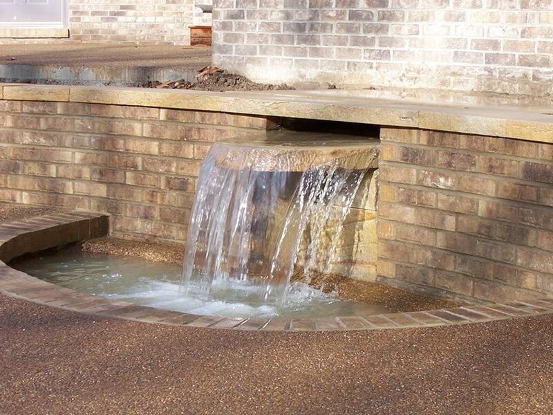 A waterfall is built into the side of a brick building.