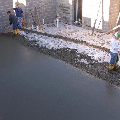A group of construction workers are working on a concrete floor