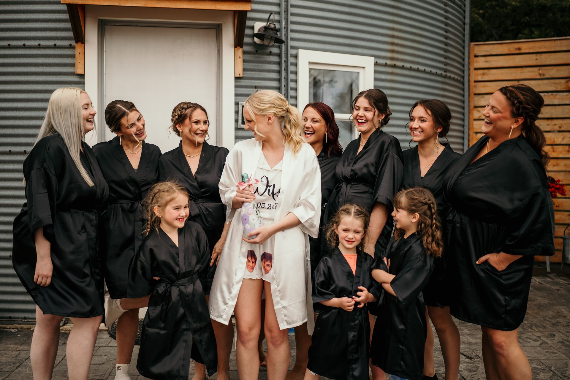 The brides and bridesmaids in front of a grain bin on the wedding day in Joice, IA.