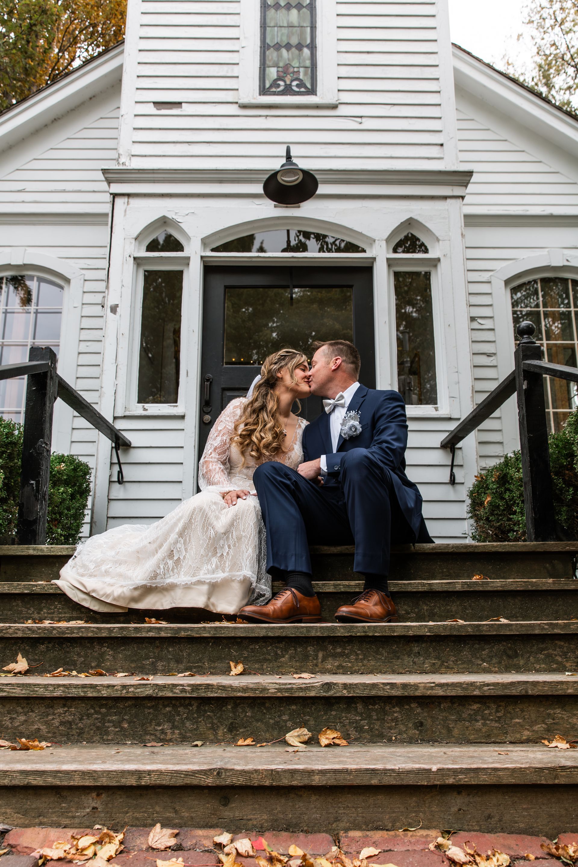 Wedding couple sharing a kiss on the front steps of the church in Pella, IA.