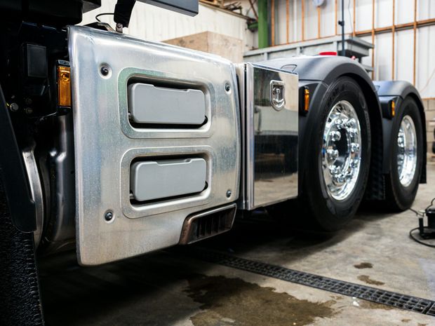 A silver semi truck is parked in a garage.