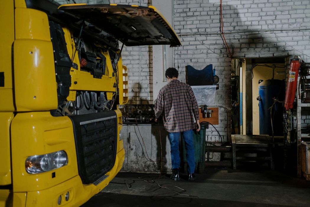 A man is working on a yellow truck in a garage.