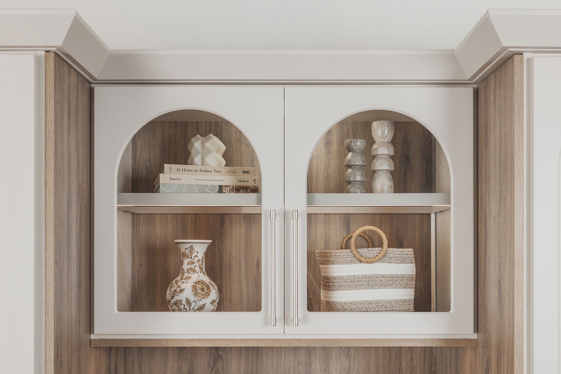 Built-in cabinet with arched shelves, white doors, and decorative jars and baskets.