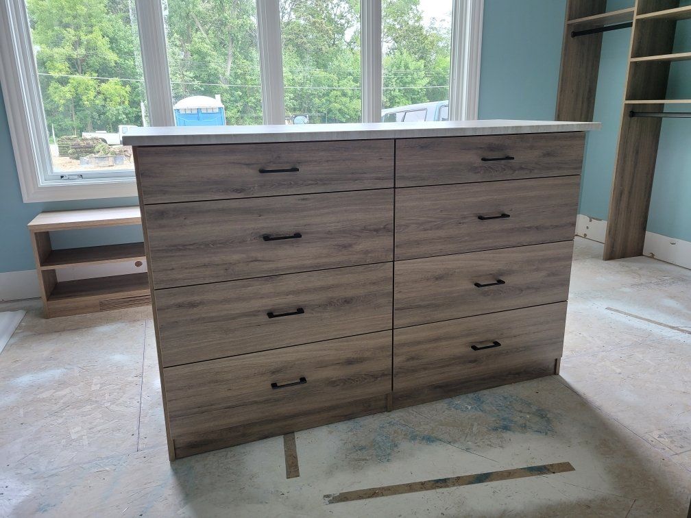 A dresser is sitting in a room next to a window.