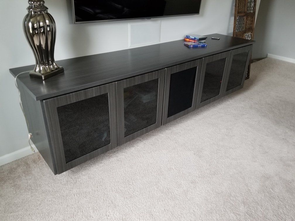 A long entertainment center in a living room with a lamp on top of it.