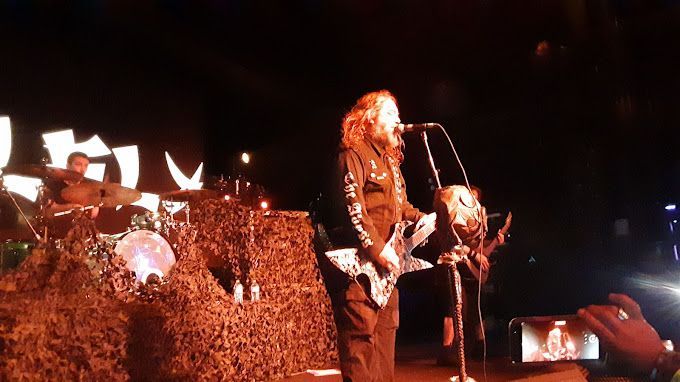 A man is singing into a microphone while playing a guitar on stage.