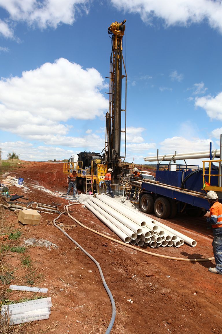 A yellow truck is parked in a field with trees in the background