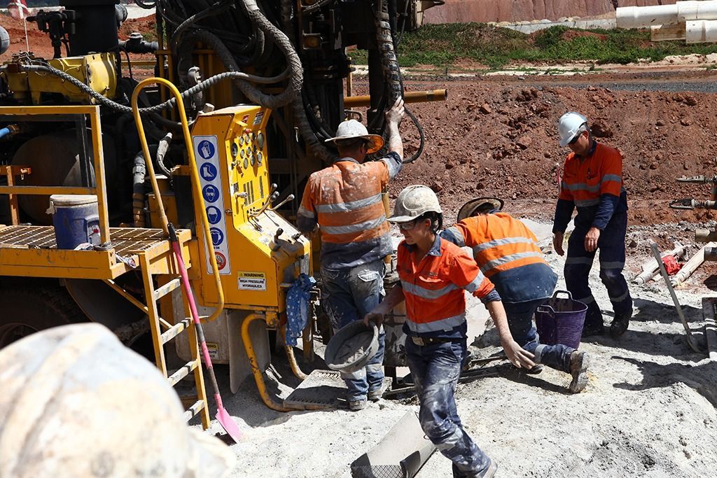 A blue truck is parked next to a drilling rig.