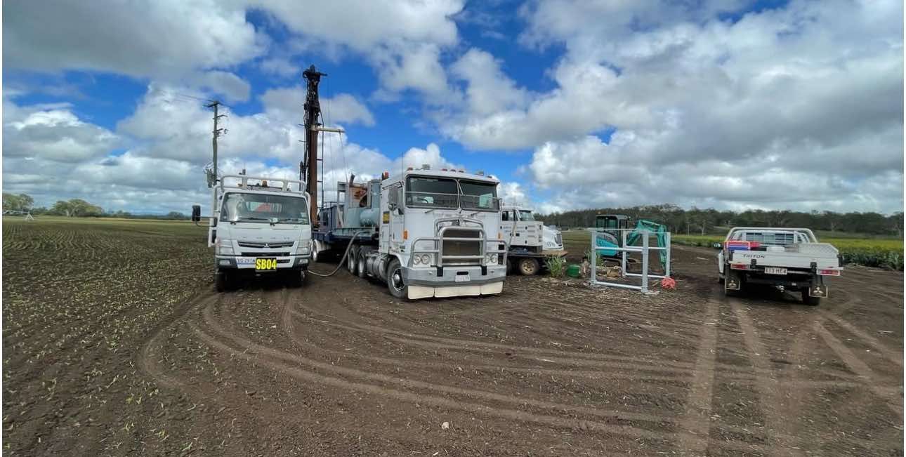 A group of trucks are parked in a field with trees in the background.