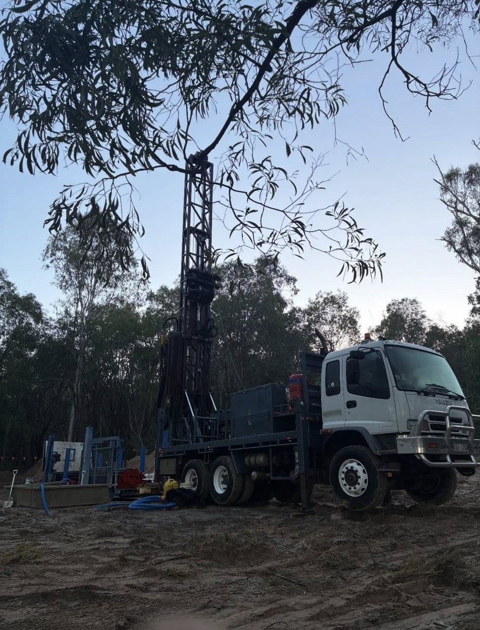 Drilling rig on a truck in a wooded area preparing to drill into the earth; daytime.