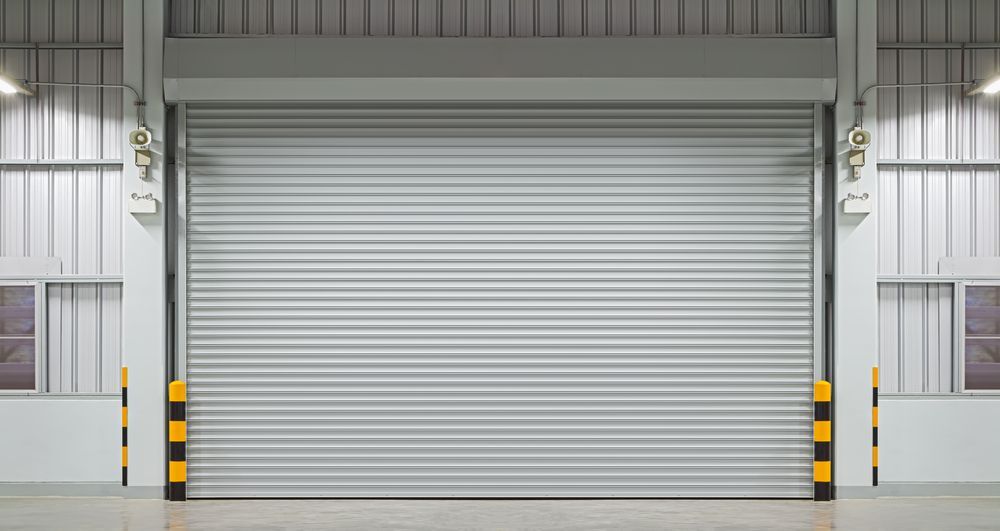An Empty Warehouse With a Large Rolling Door — Window Coverings in Cardiff, NSW