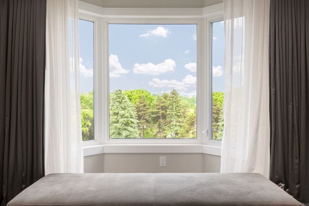 Bay Window With Drapes And Curtains And View Of Trees Under Summer Sky — Window Coverings in Cardiff, NSW