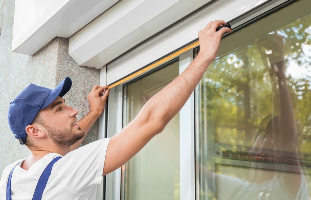 Man Measuring Window Prior To Installation Of Roller Shutters Outdoors — Window Coverings in Cardiff, NSW
