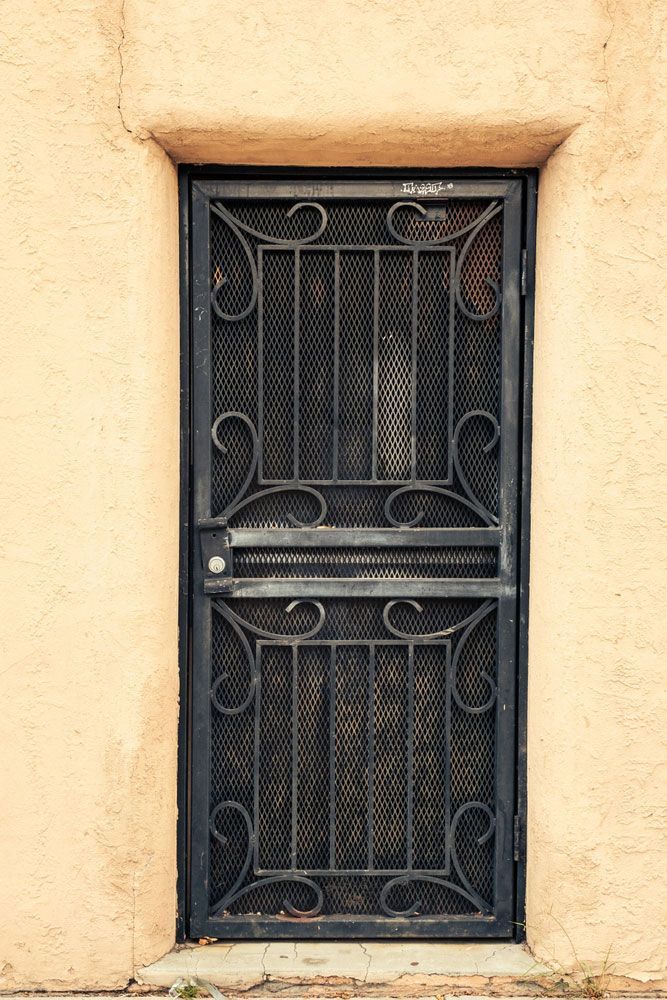Black Metal Entrance Door Design On A Brown Wall And Security Screen Door — Wholesale Window Coverings in Newcastle, NSW