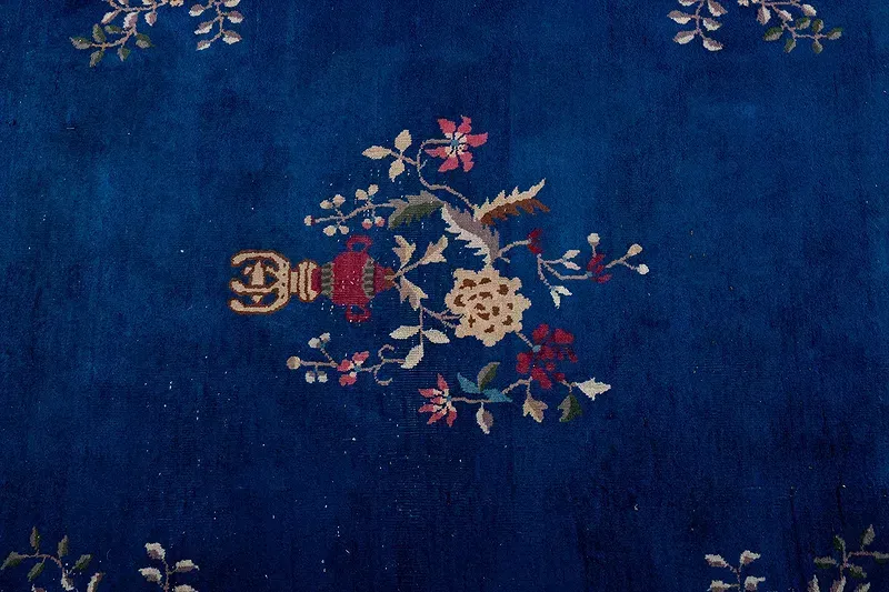 A blue rug with a bird and flowers on it
