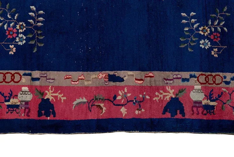A blue and pink rug with elephants and flowers on it