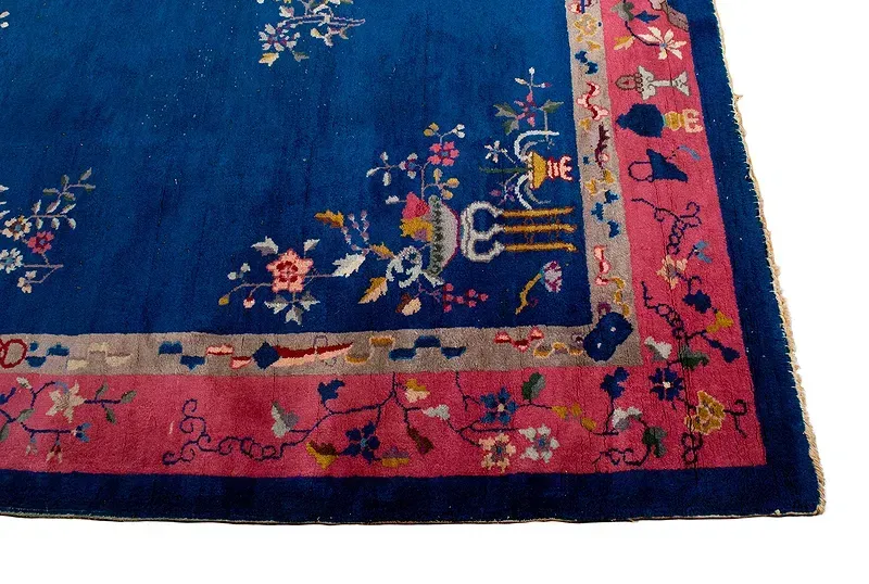 A blue rug with a pink border and flowers on it