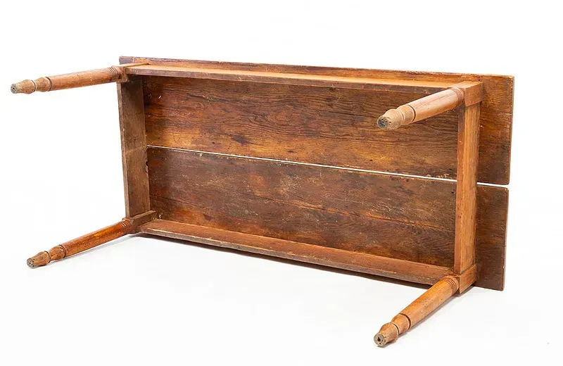 The bottom of a wooden table with wooden legs on a white background.