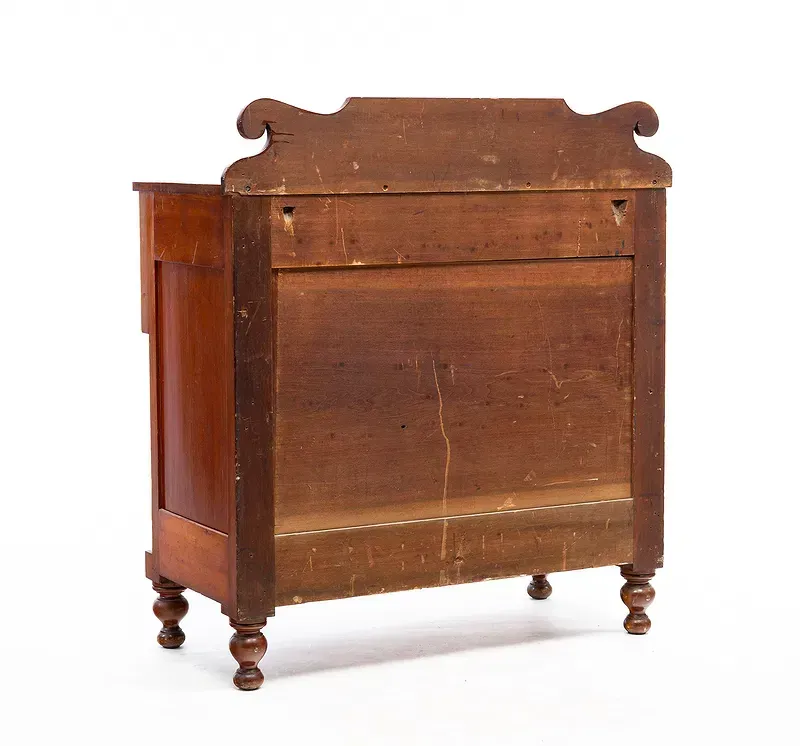 The back of a wooden dresser with a white background